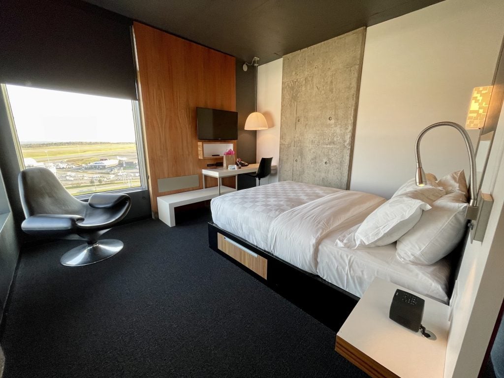 A hotel room with a big corner window overlooking the airport runways.