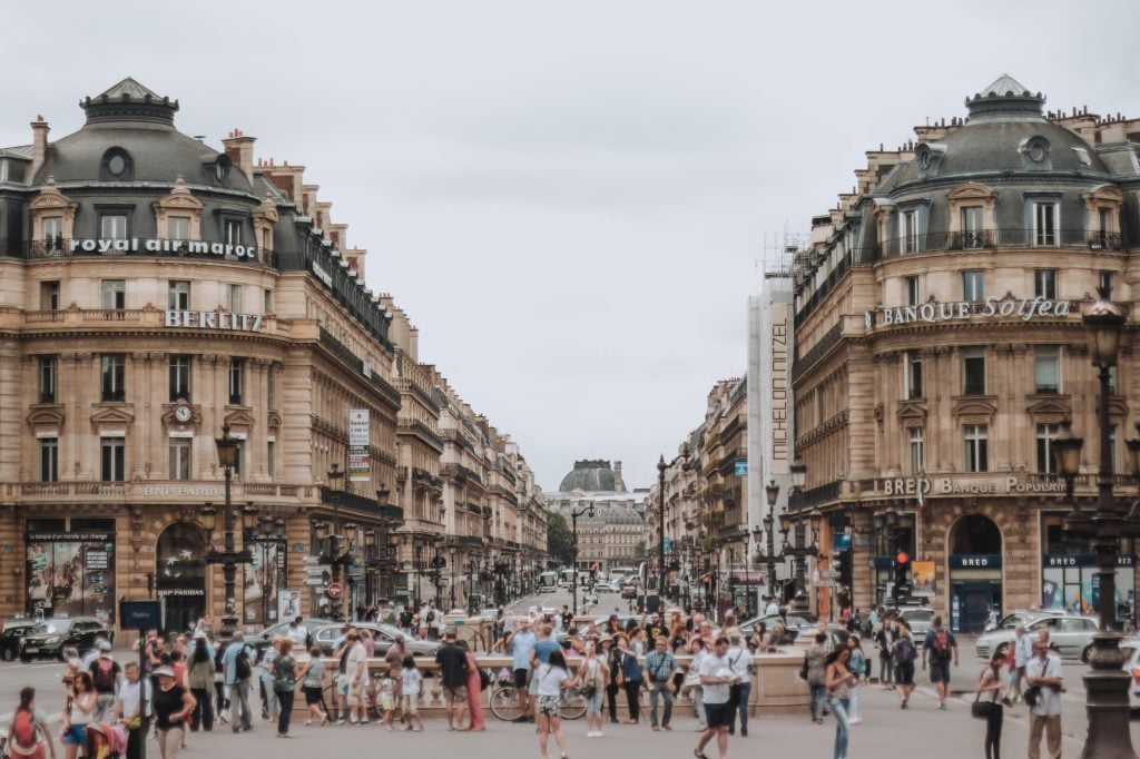 A view down Avenue de l'Opera busy with pedestrians and traffic on a summer day with high clouds. Cloudy weather