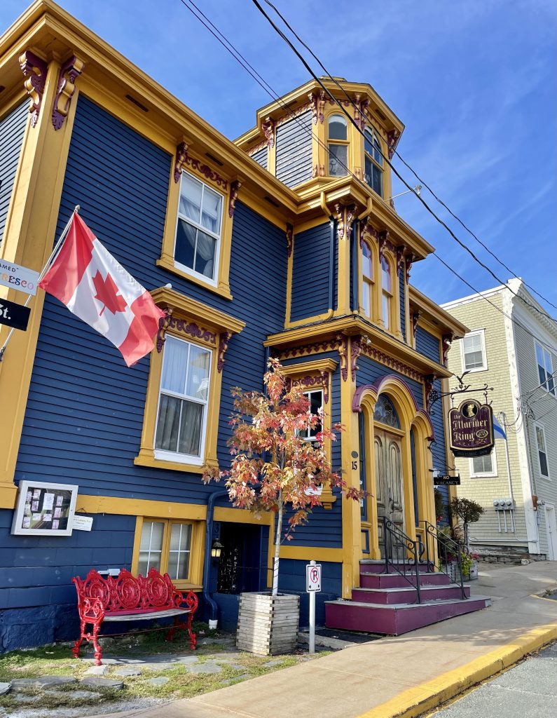 A big navy blue and yellow Victorian building with a Canadian flag flying.