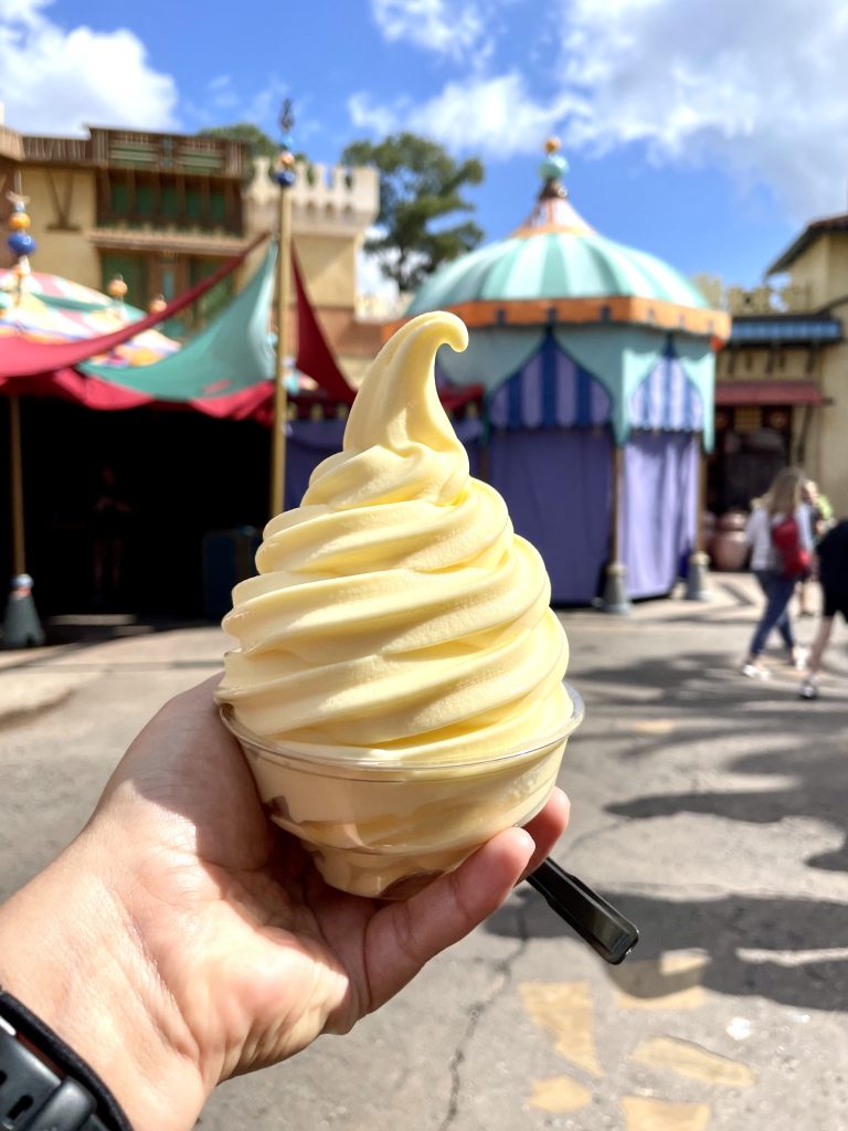 A yellow soft serve Dole Whip held in Kate's hand.