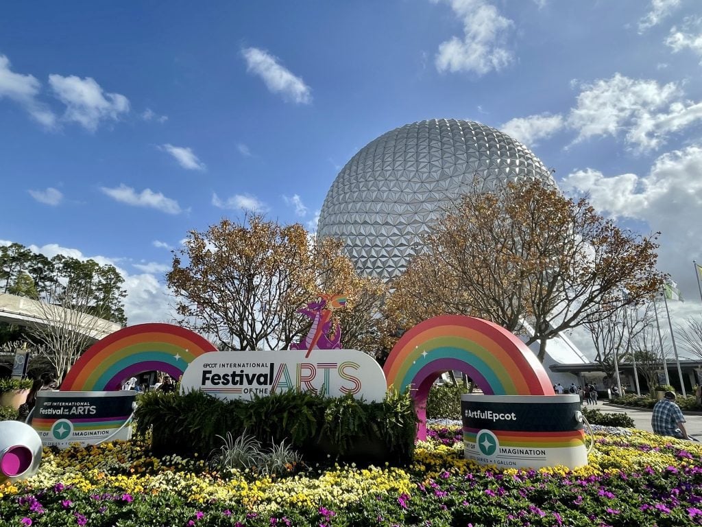 A big sign reading Festival of the Arts between two rainbows, in front of Spaceship Earth at Epcot.