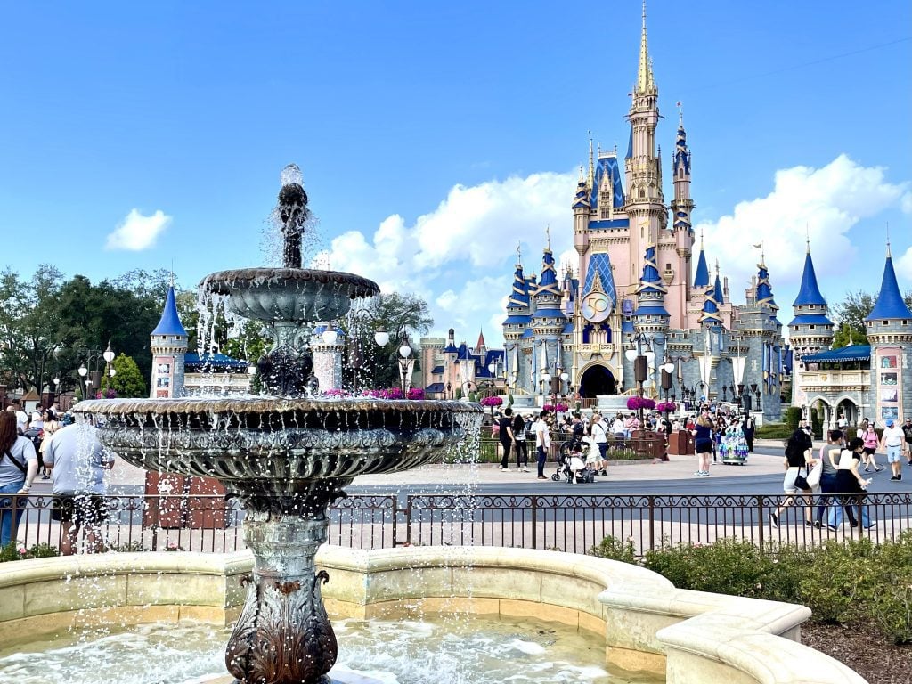 A gray wrought-iron fountain in the foreground, and behind it is Cinderella's castle, all pink and gray with blue steeples and gold trim, decked out extra special for the 50th anniversary.