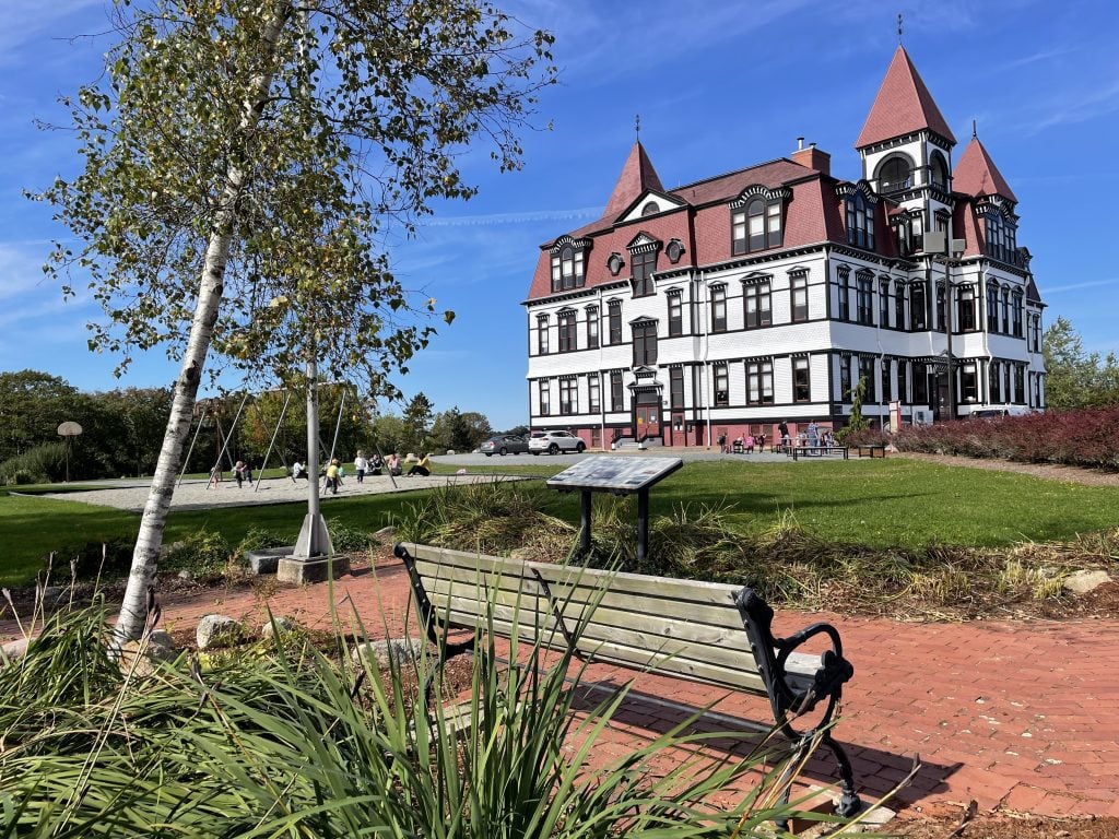 A big white school with espresso-brown trim around each window, and pointy red-shingled towers.