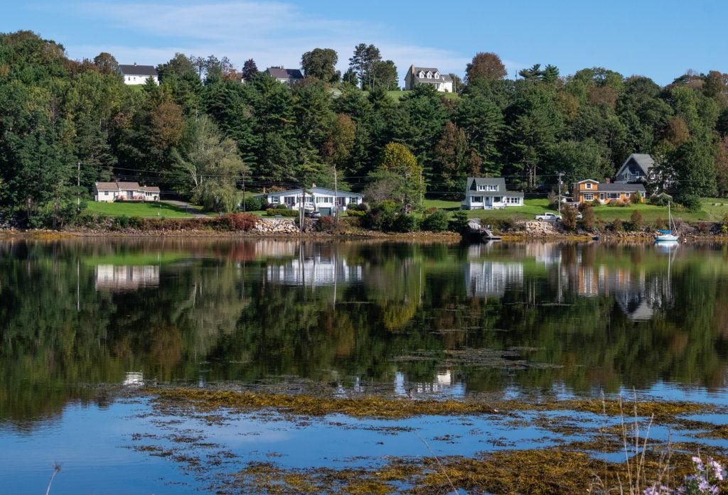 Several cottages reflecting on a calm lake.