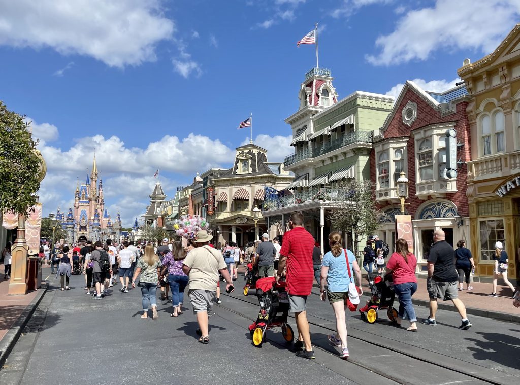 Crowds of people, mostly in jeans or shorts and sneakers, walking down Main Street toward Cinderella Castle.