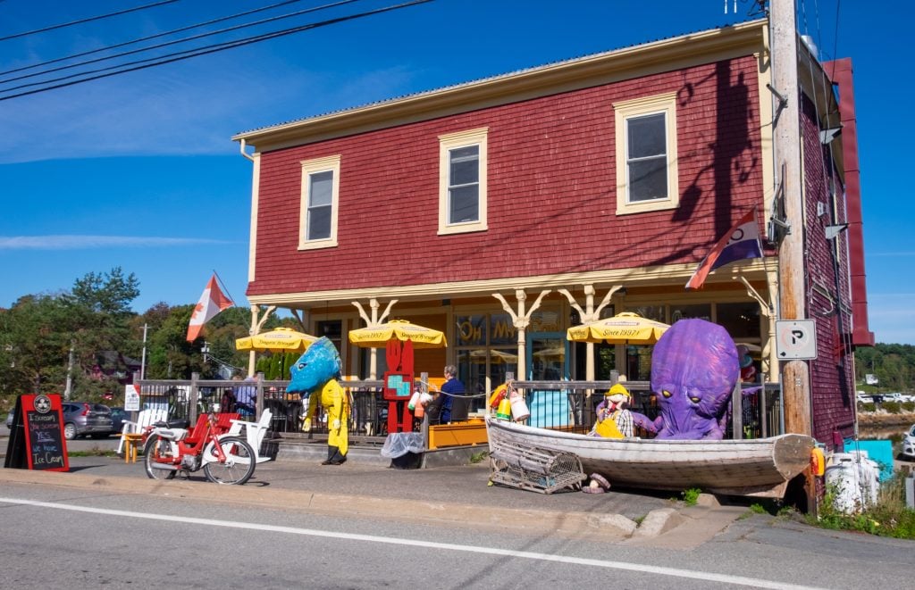 A big red and yellow building next to the water with papier-mâché octopus, fish, and fishermen outside.