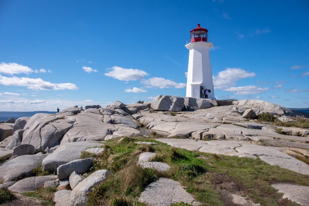 A close-up view of the white lighthouse on the gray rocks.