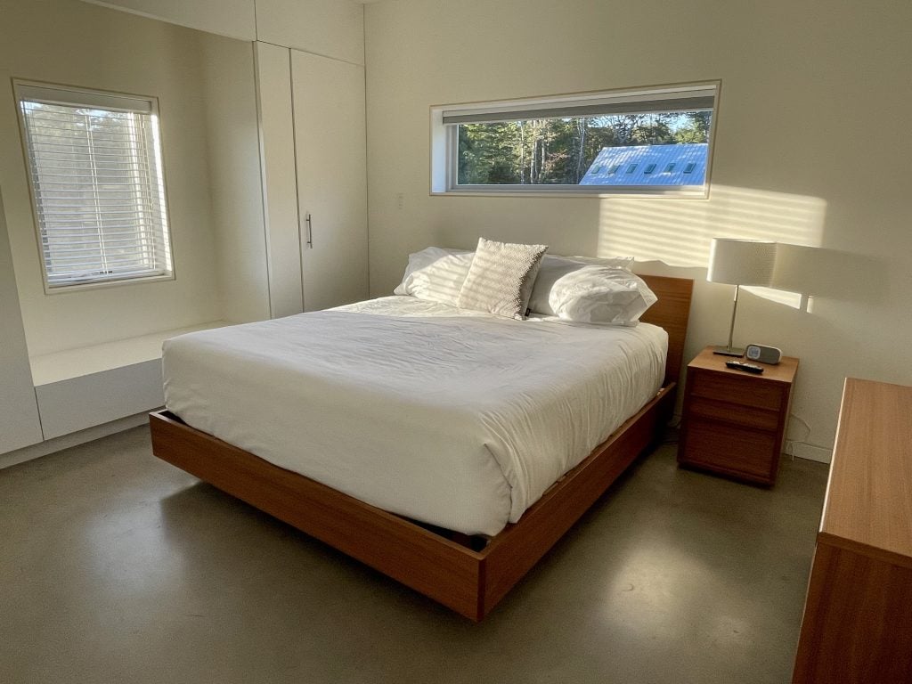 A simple white hotel room with wood furniture.