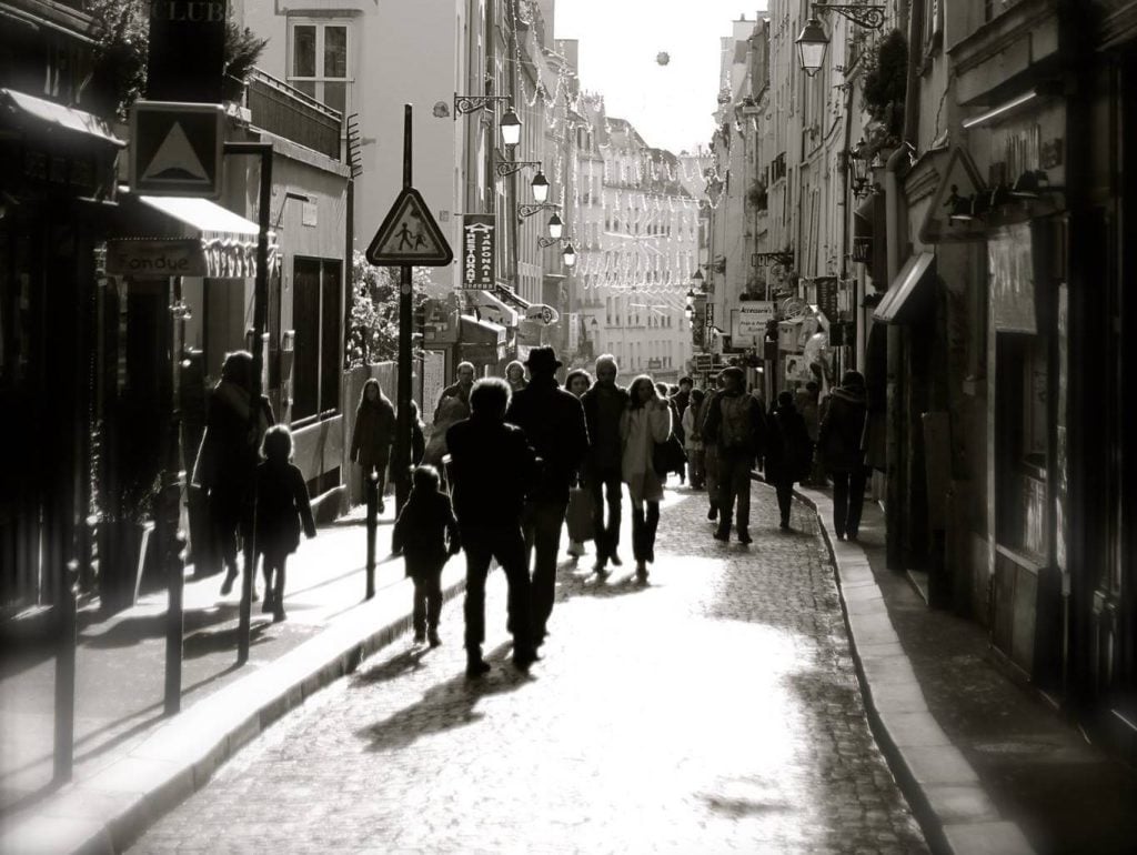 A black and white photo of people walking down a pedestrian street in Paris