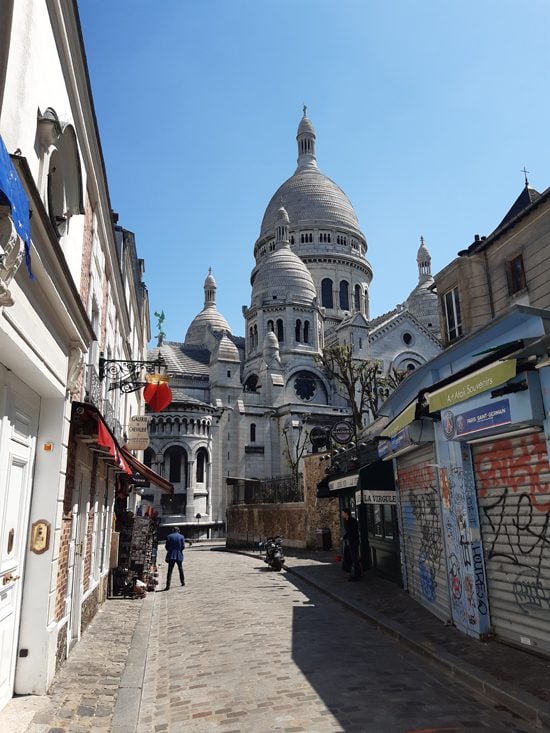Street view of Rue Saint-Rustique with the Sacre-Coeur Basilica in the background