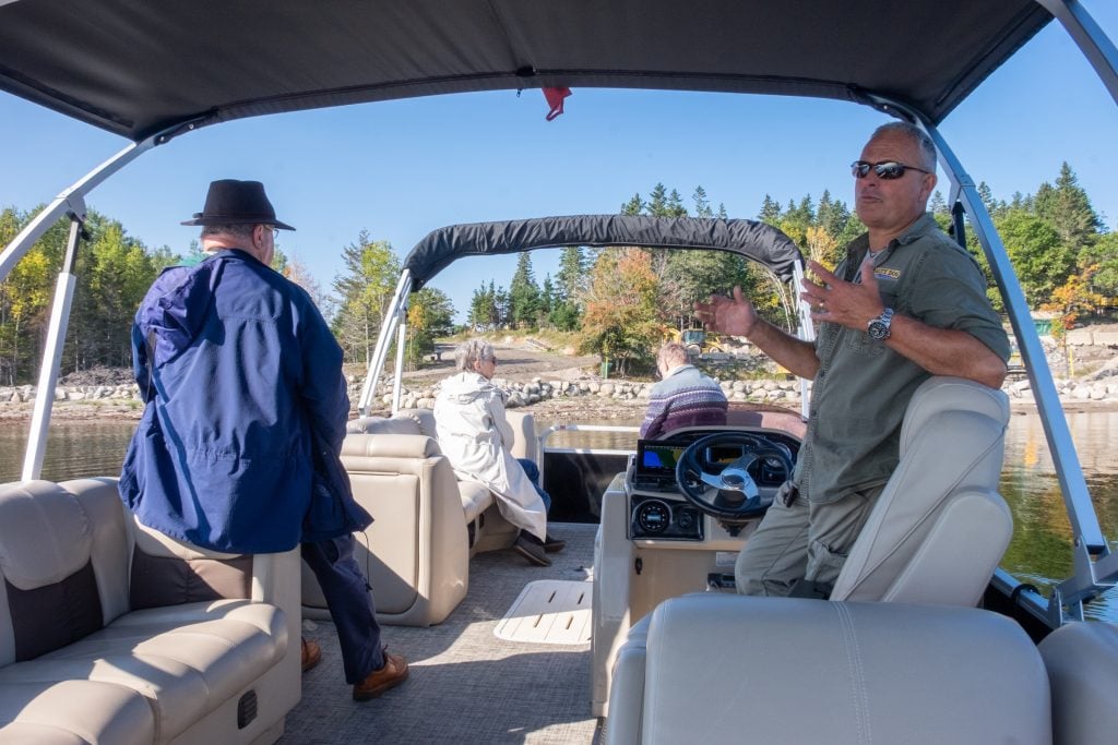 A boat ride to Oak Island on a very nice boat with leather seats, four people sitting in various areas.