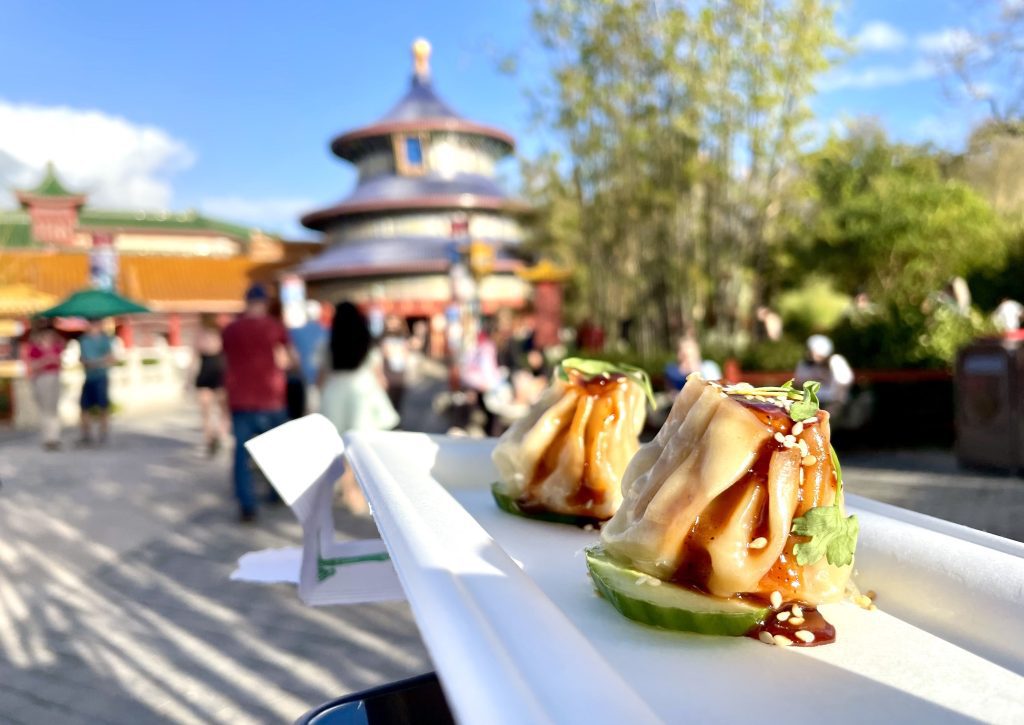 A plate of two shu mai dumplings, with a Chinese pagoda in the background.