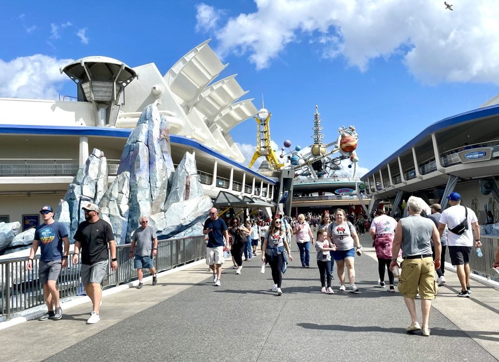 People walking into the entrance of Tomorrowland, with dated-looking images of planets and spaceships.
