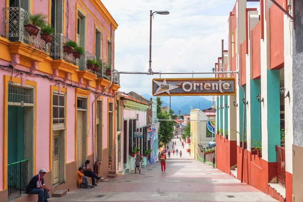 A Cuban street with salmon-colored buildings and green doors