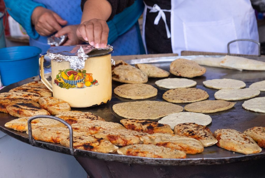 A large skillet covered with tortillas and Gorditas, as well as a big jar of lard.