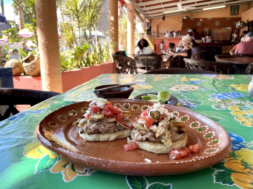 Two sopes (thick corn tortilla-like things) topped with refried beans, chicken, tomatoes, cheese, and jalapeños.