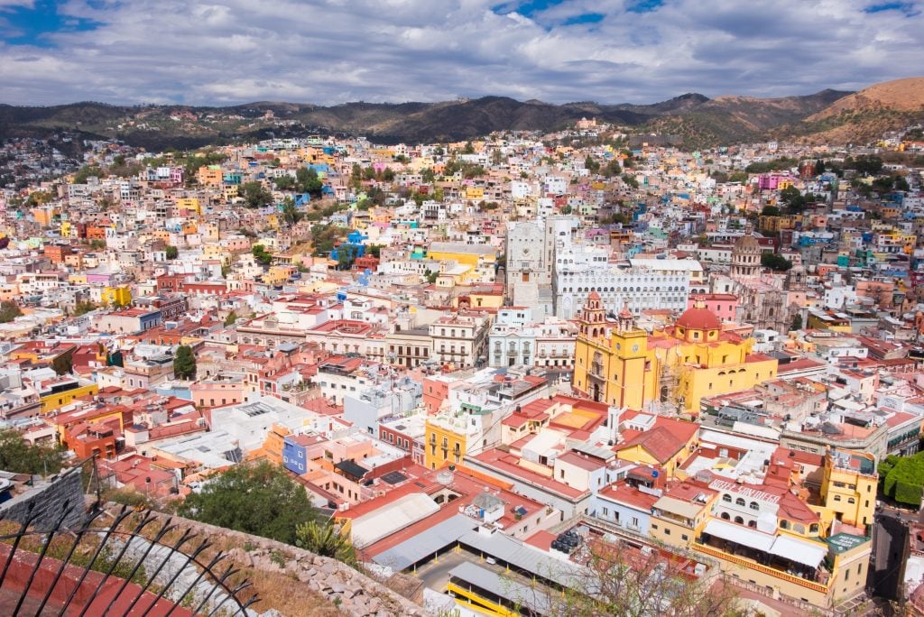 A view of Guanajuato from above, an endless landscape of brightly painted square houses (and a yellow and red cathedral) leading up into the mountains.
