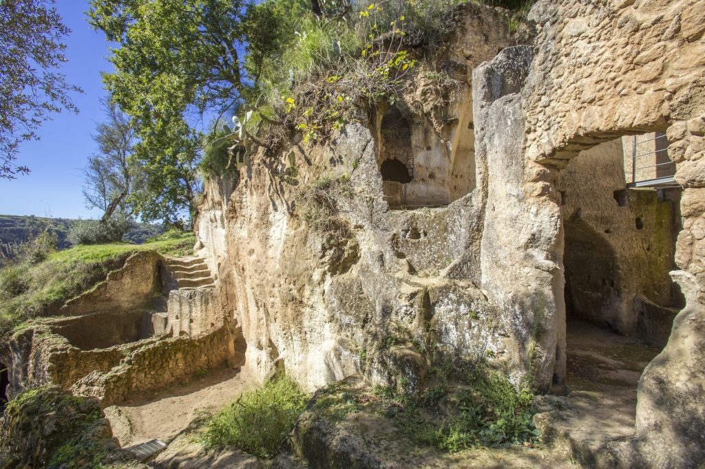 A stone complex of caves, with doorways and stairs cut into the rock face.