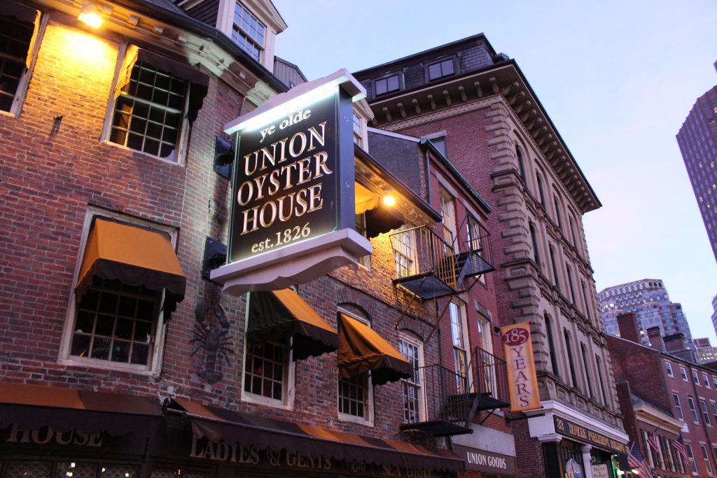A historic brick building in the evening, with a sign that says Union Oyster House and a few street lamps