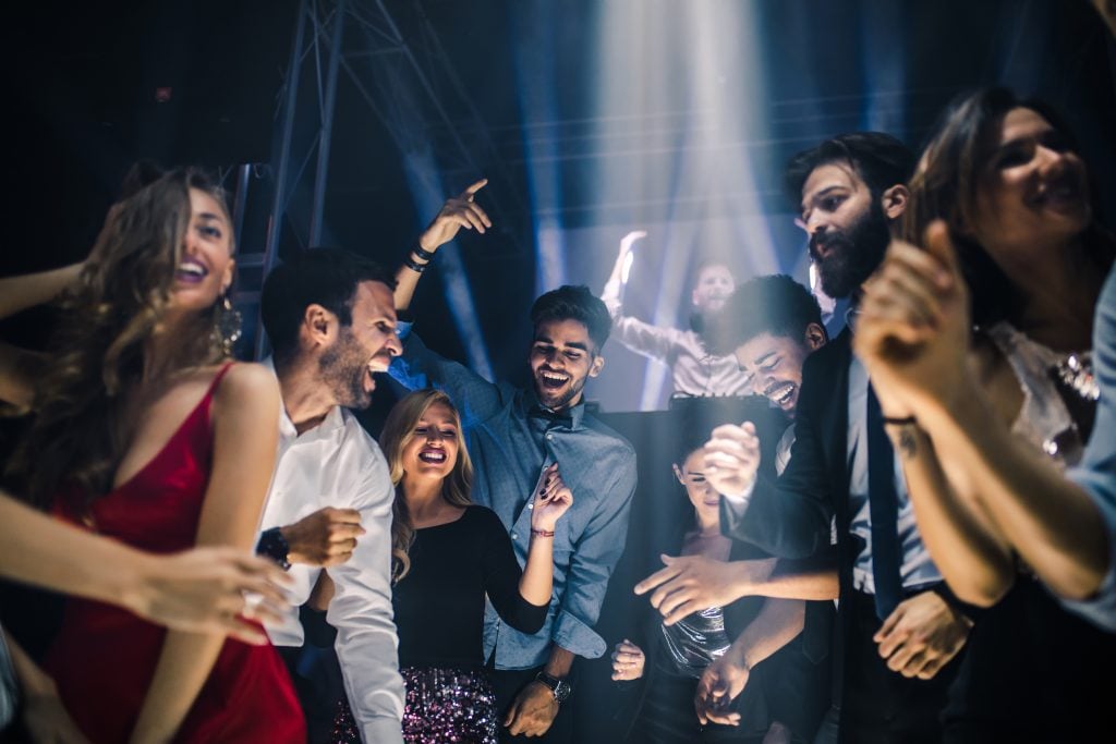 A crowd of young people dressed up and dancing in a club.