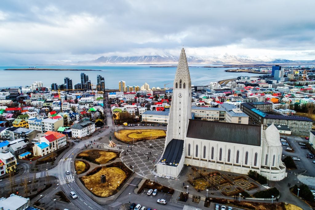 Hallgrimskirkja Church, pointy and gray, in the front, surrounded by the colorful small buildings of Reykjavik (and several tall condo buildings on the waterfront).