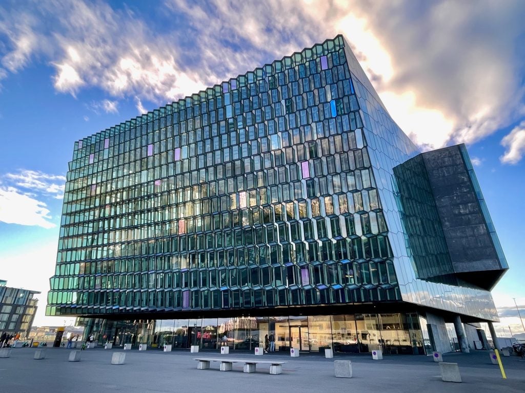 Harpa: a tall light blue glass building with walls that look like honeycomb-shaped panels of glass layered on top of each other.