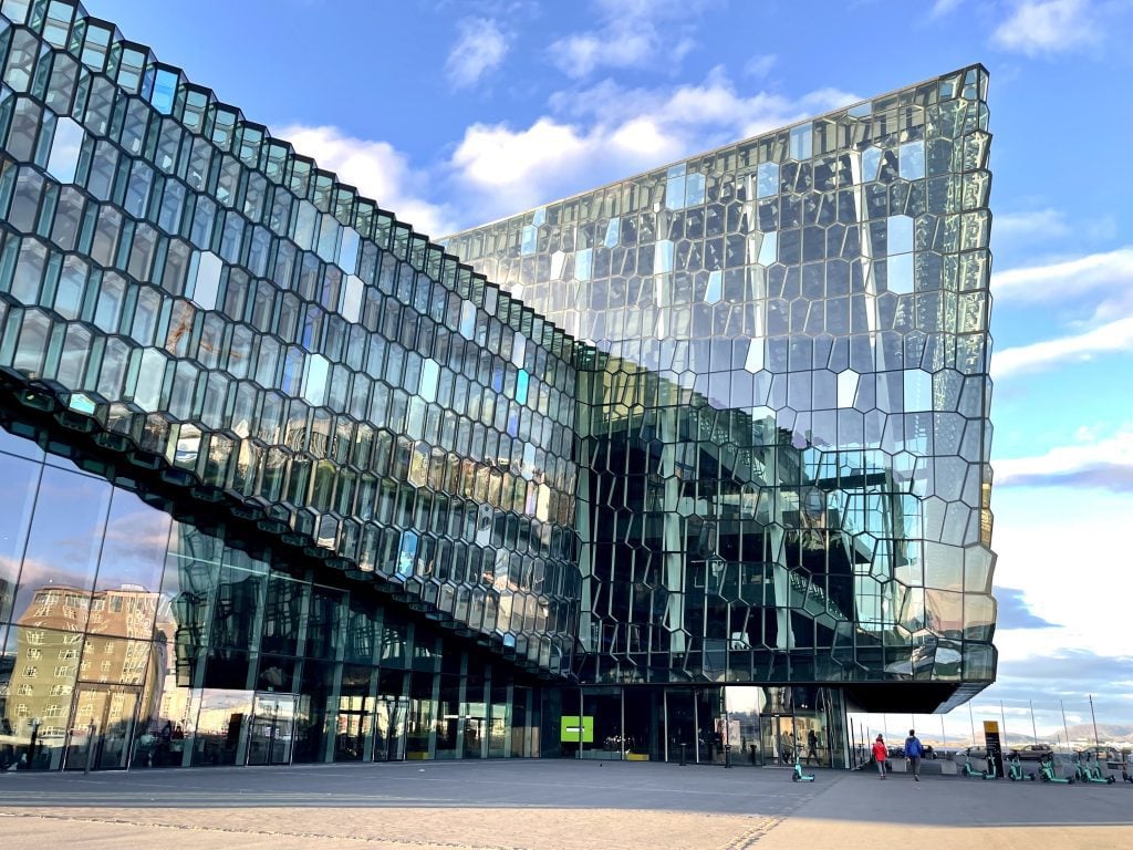 Iceland's modern Harpa building: perpendicular walls of hexagon-shaped glass panels glinting blue in the midnight sun.