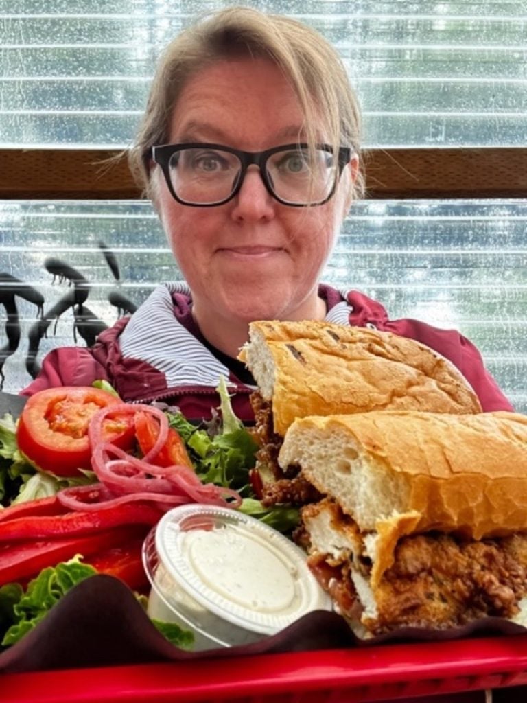 Sue behind a huge plate of food, with a sandwich and salad