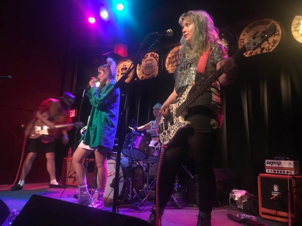 A band performing on stage with a female lead holding a guitar