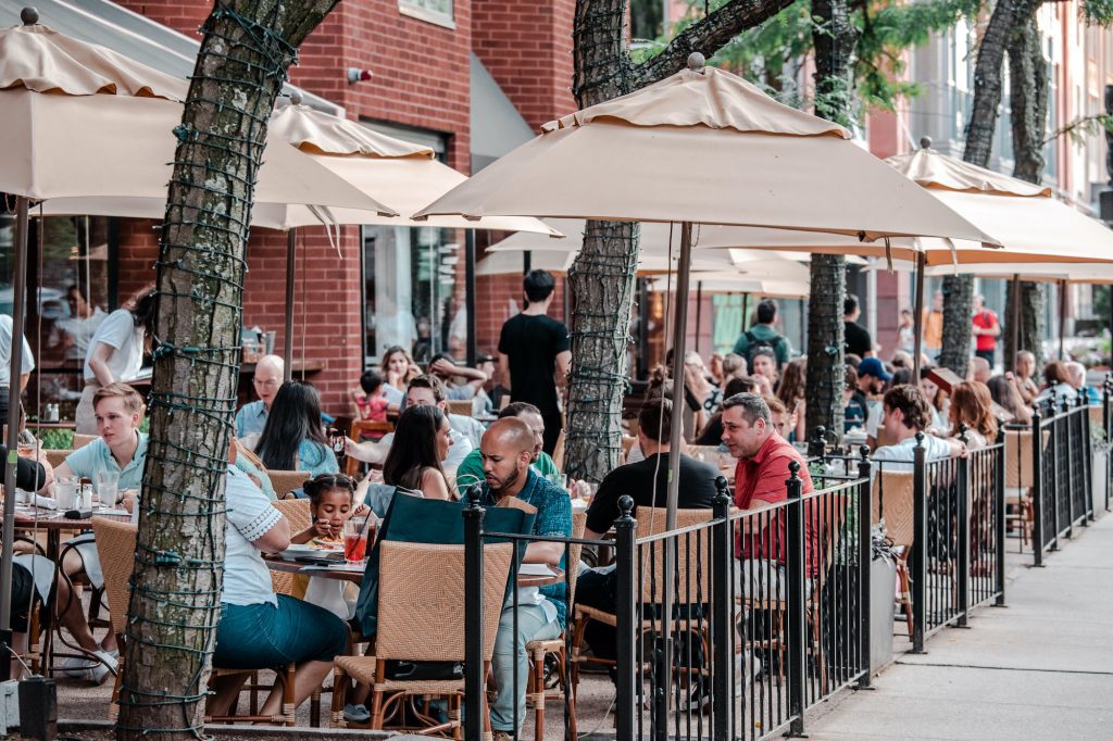 People sitting at dining tables on a patio on Newbury Street.