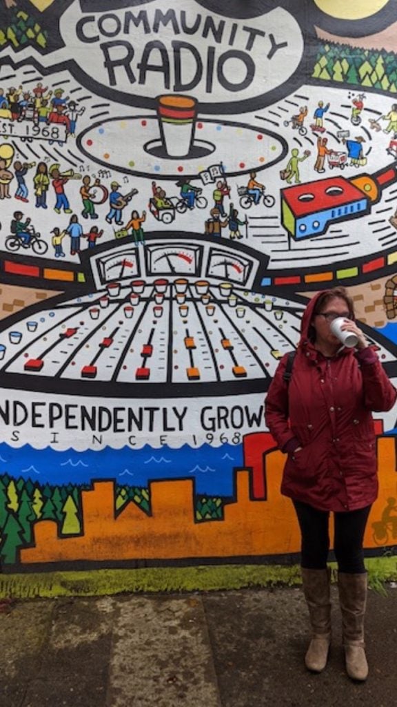 Sue sipping coffee in front of Portland street art