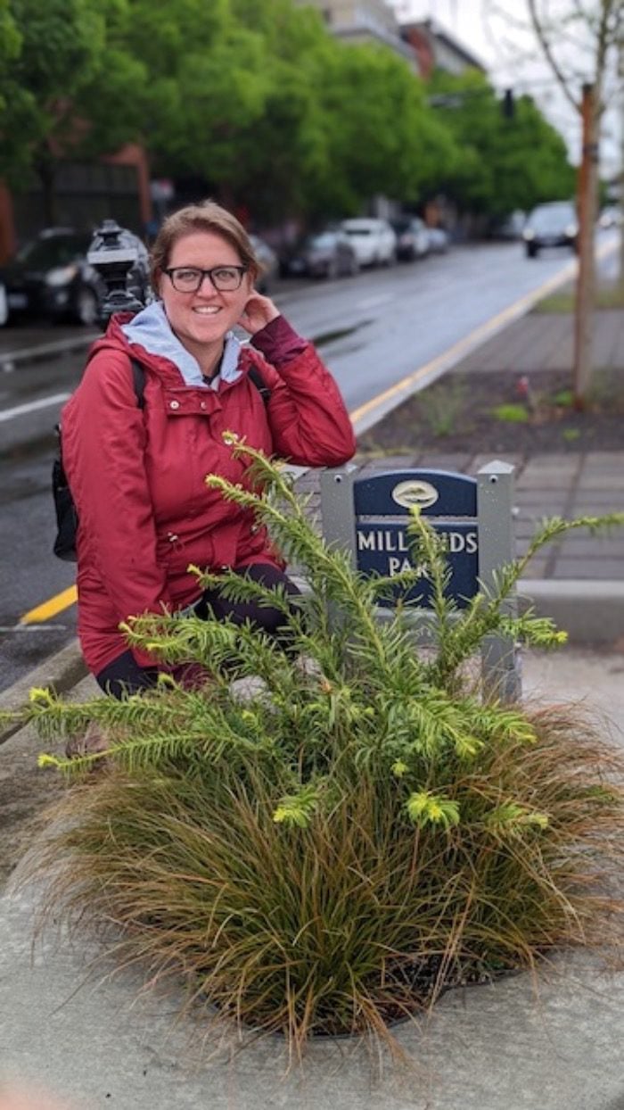 Sue standing next to a plant at Mills End Park in Portland