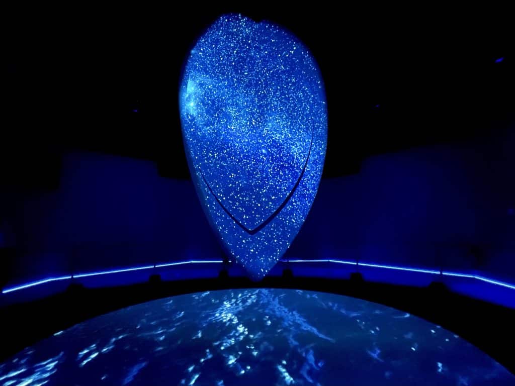 A teardrop-shaped screen in a dark room covered with images of stars.