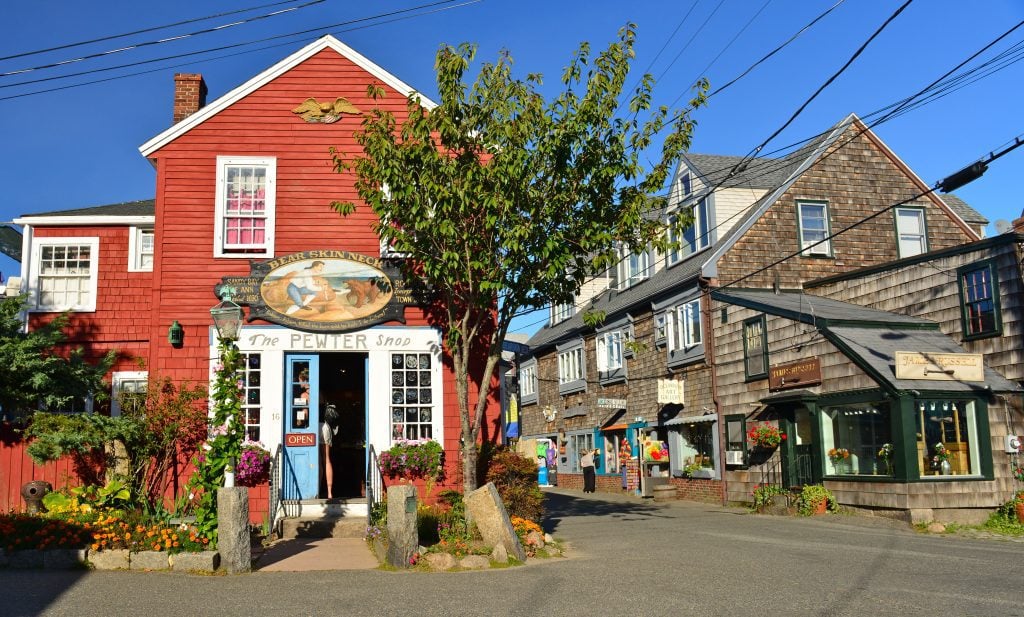 A bright red house labeled The Pewter Shop next to weathered brown clapboard buildings.