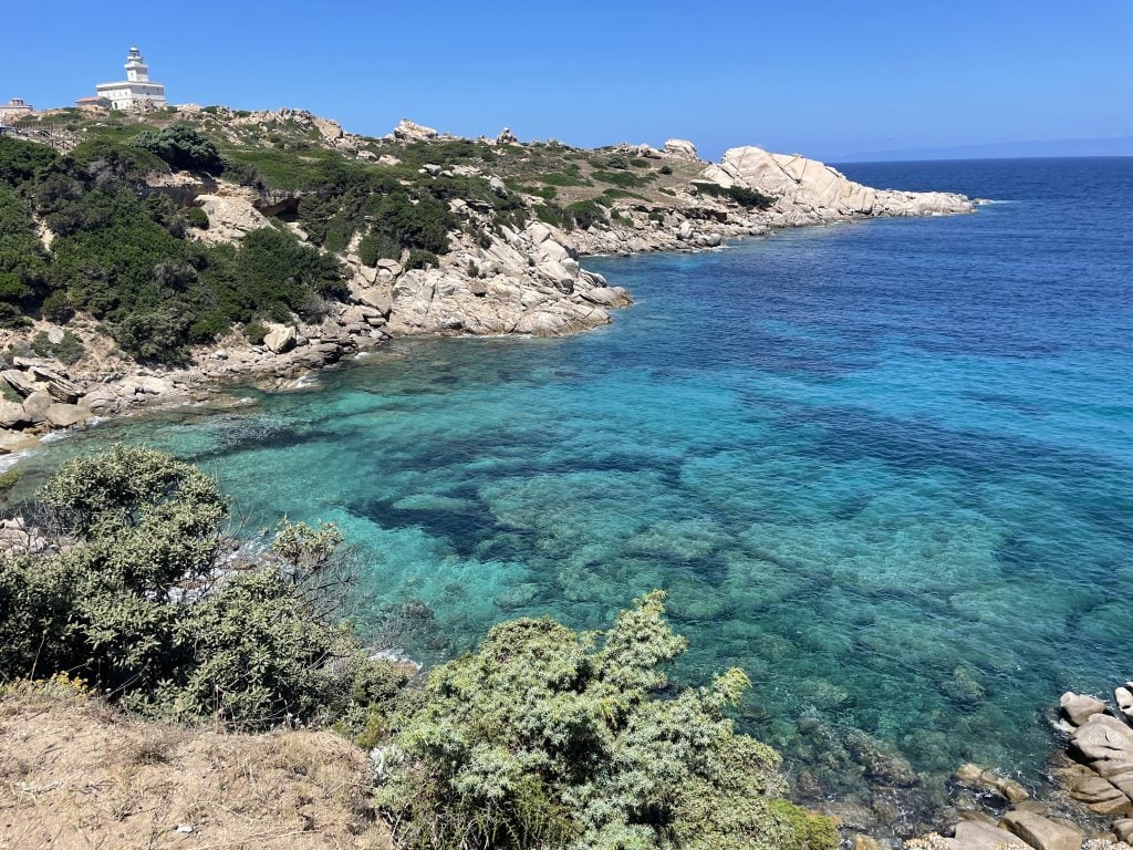 A rocky coastline surrounding bright, clear, teal-blue water.