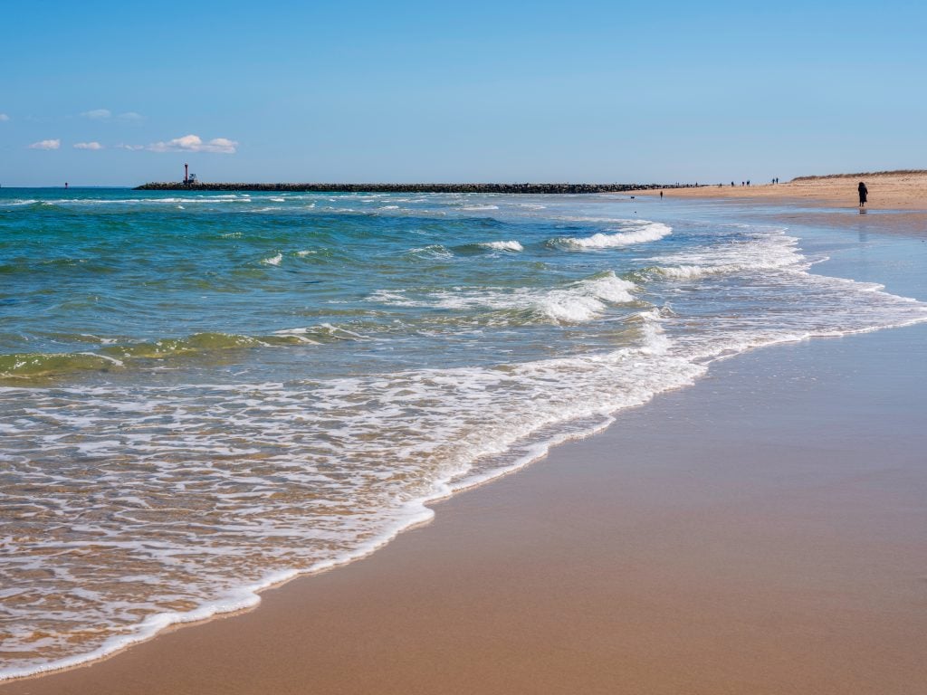 Waves cascading on a wide sandy beach.