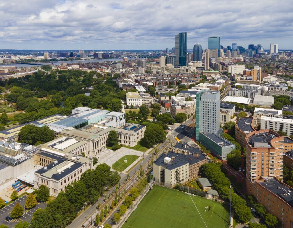 A bird's eye view of Boston, with a big museum on a lawn in the foreground and skyscrapers in the distance.