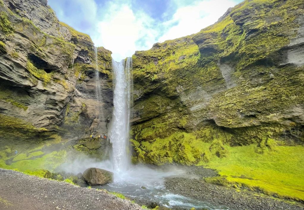 A gentle waterfall falling in a mossy green canyon.