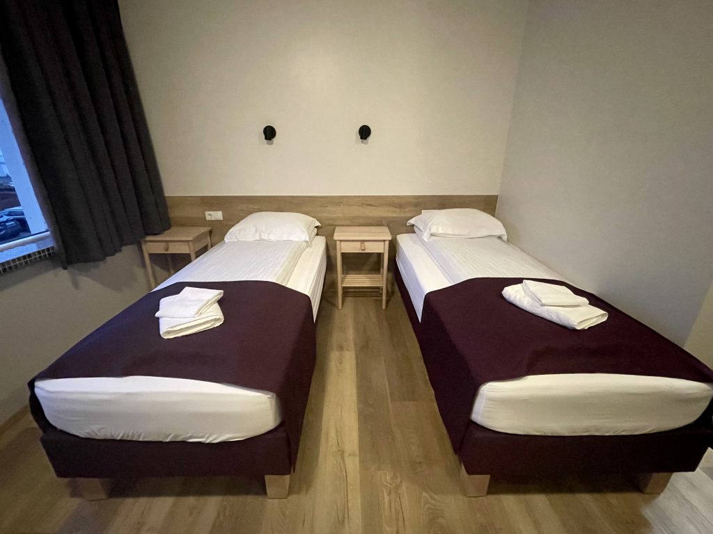 Two simple twin beds in a very plain hotel room.