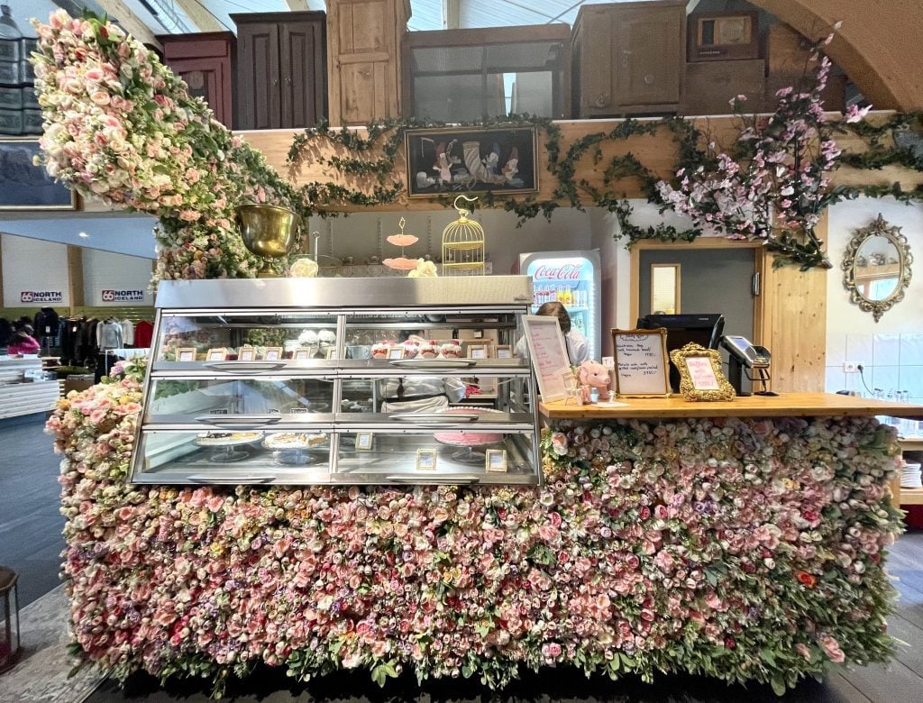 A counter at a cafe covered with thousands of pink fabric flowers.