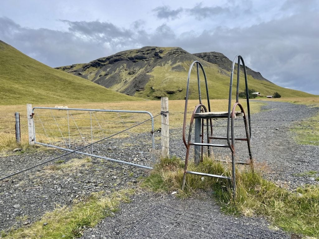 A small metal ladder crossing a wire fence.