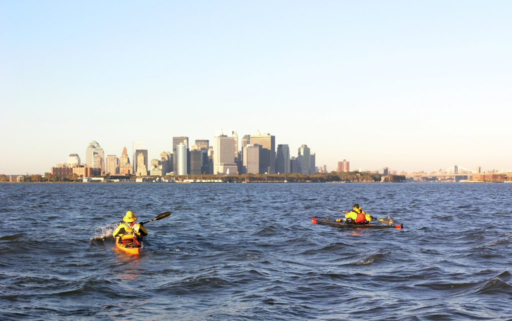 Two yellow kayaks on water in front of the NYC skyline