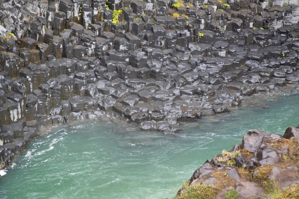 A close-up of super-short hexagonal columns sticking out of the turquoise water.