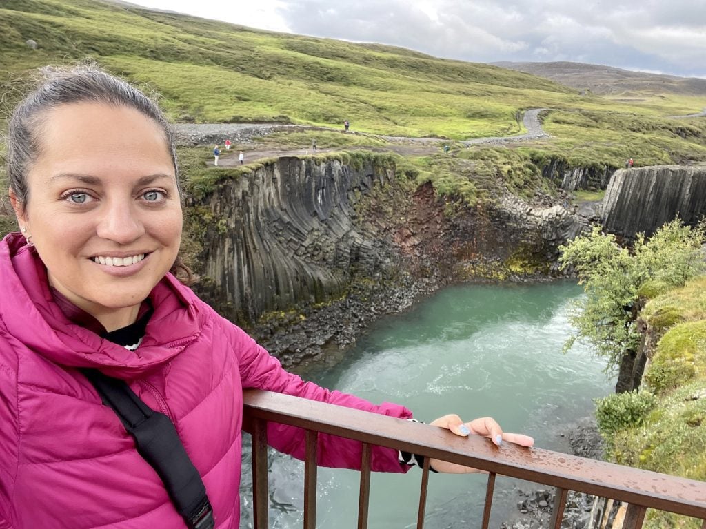 A much dryer Kate taking a selfie in front of the canyon in just her hot pink coat.