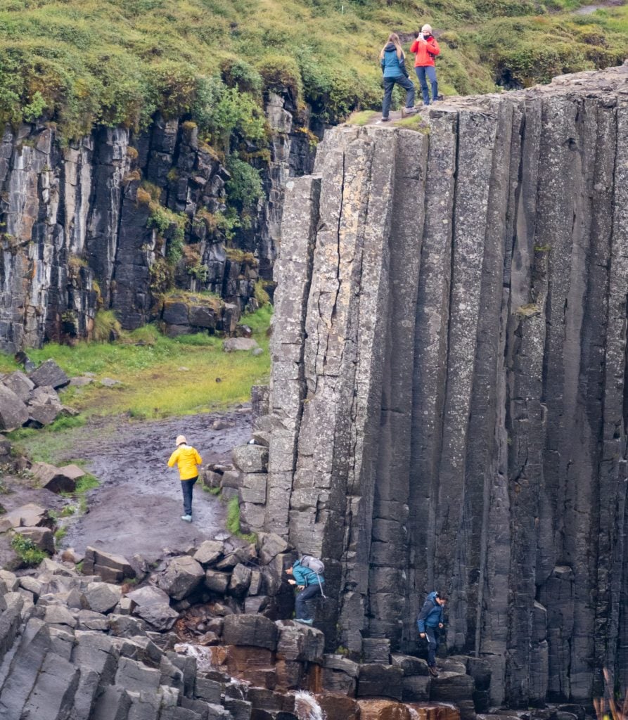 Two people posing for a selfie on top of a very tall, very narrow piece of rock above the canyon.