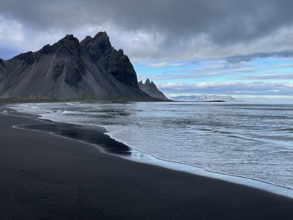 A close up of the calm sea encroaching on the black sand.