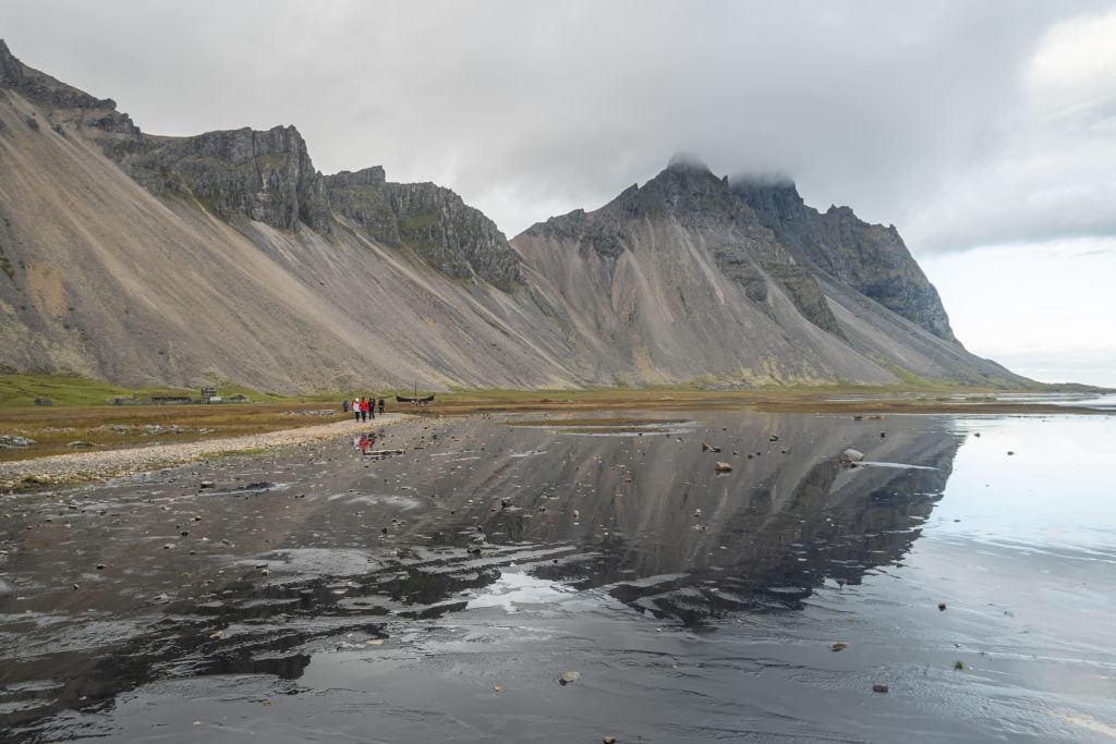 A spiky gray mountain reflecting itself in still water.