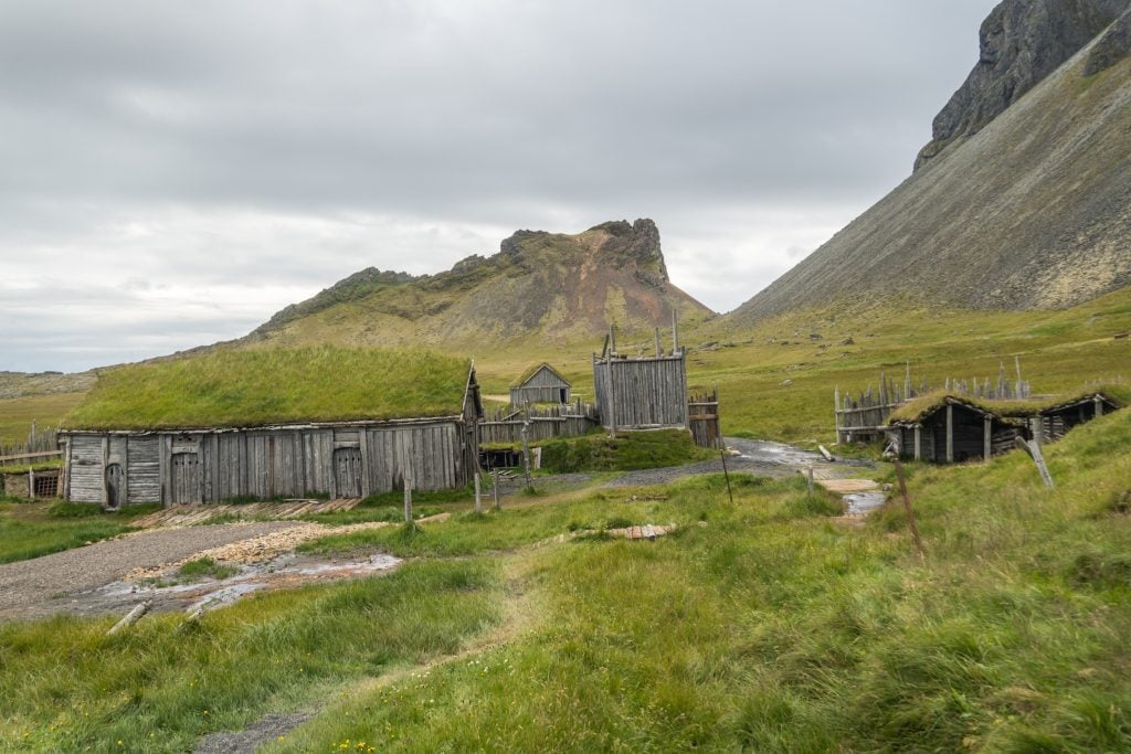 A village of falling-apart wooden houses with grass roofs.