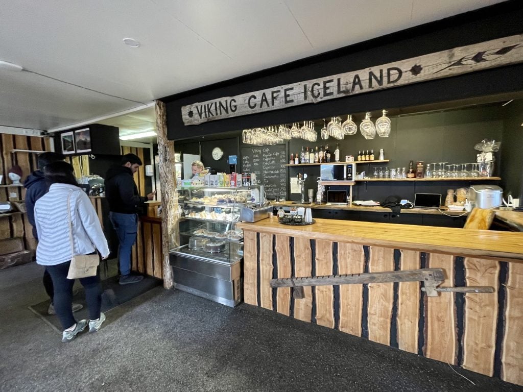 The cash register at a cafe with a wooden sign reading VIKING CAFE ICELAND on the wall.