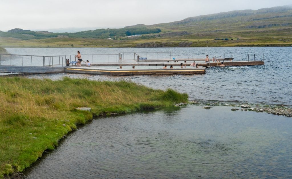 Two floating pools in the distance beyond the grassy bank of the lake.